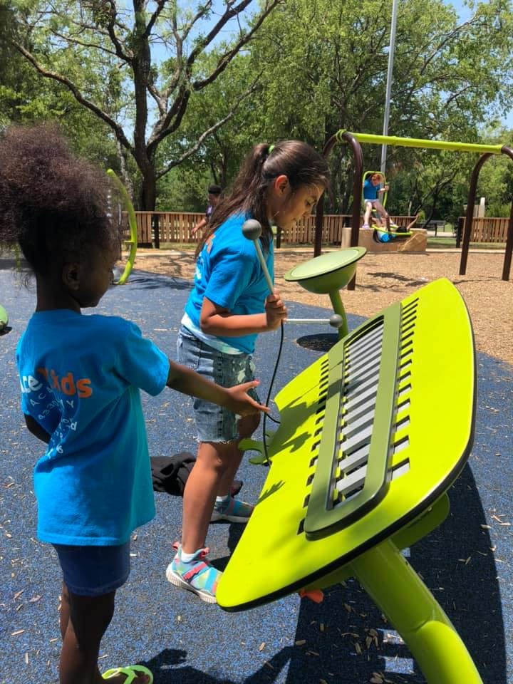 Two children playing with outdoor musical instruments