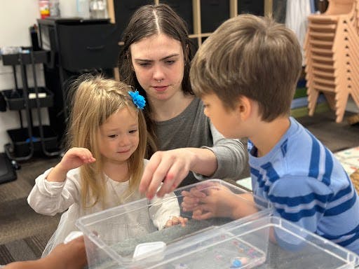 Person and two children looking into a clear container