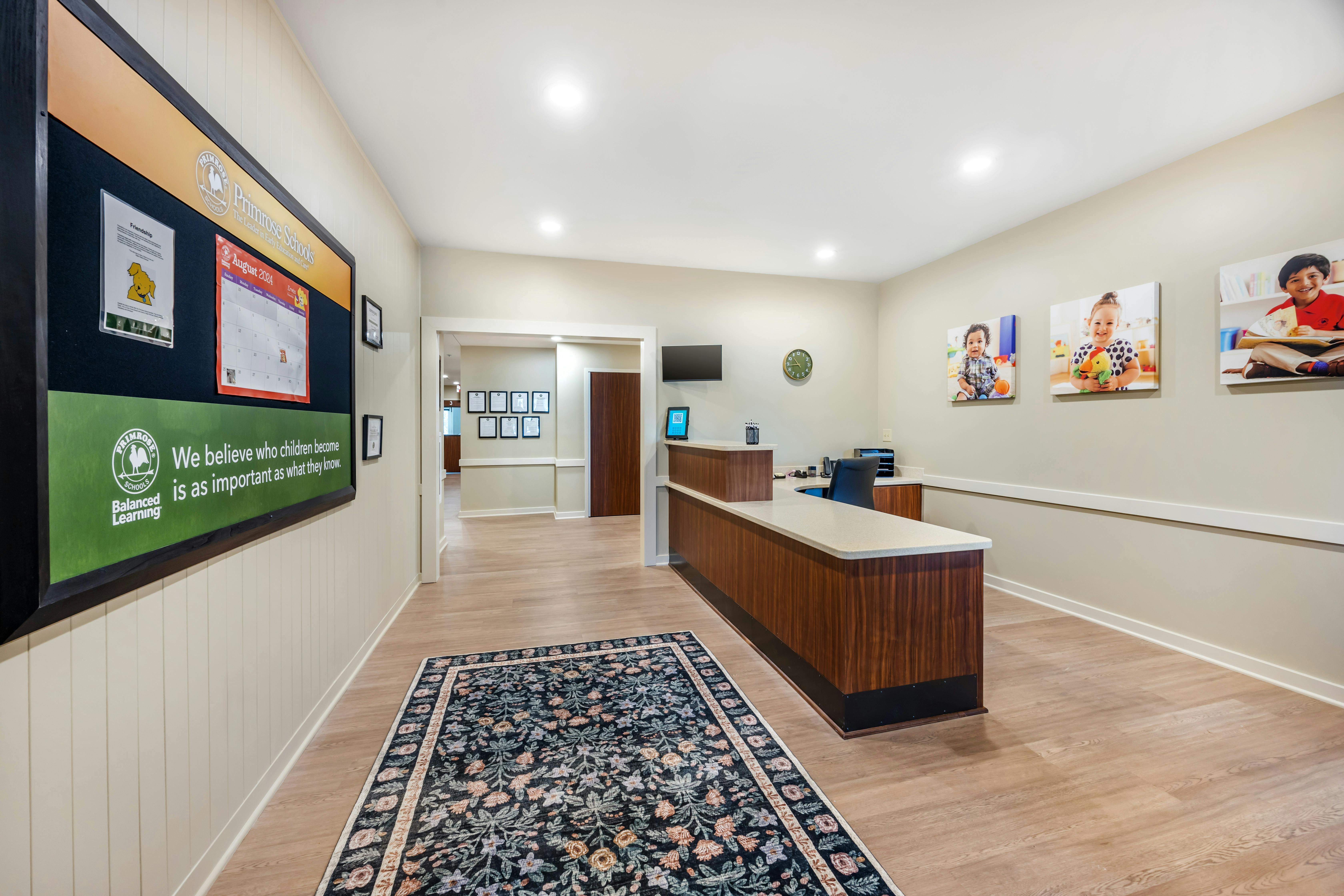 An empty reception area with a large bulletin board and child photos on the wall
