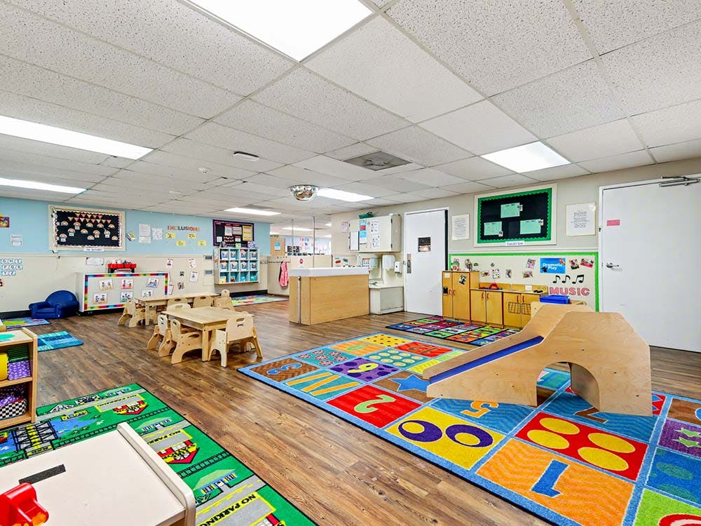 Children's play area with colorful rugs, small tables, and play equipment