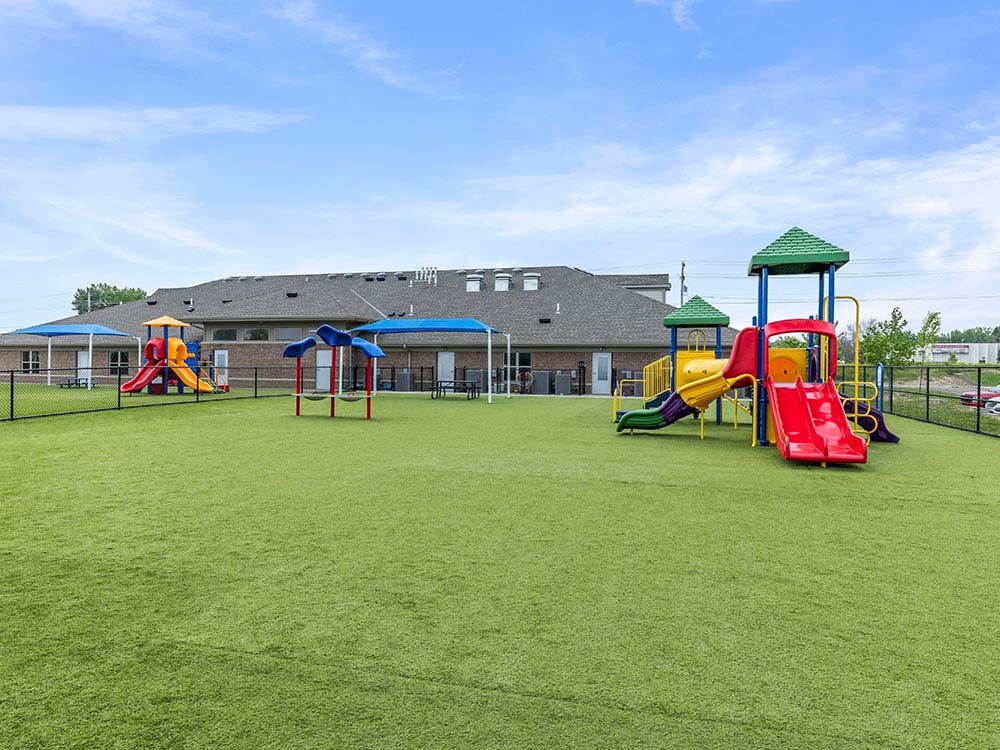 Playground with green turf and two colorful play structures