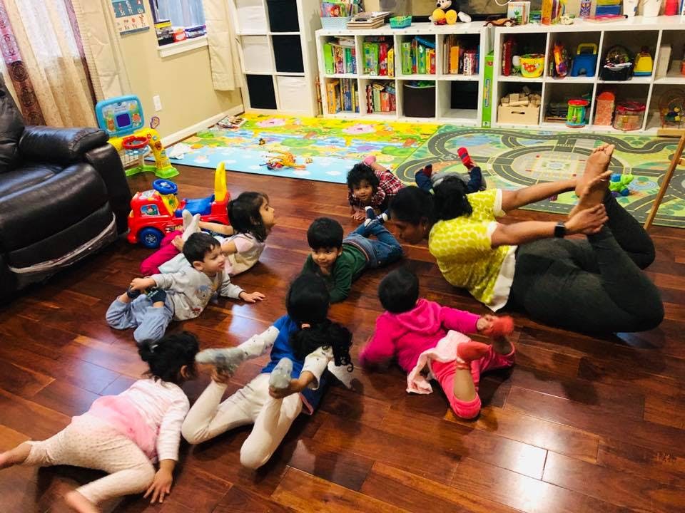 Adult and children doing yoga poses on a wooden floor