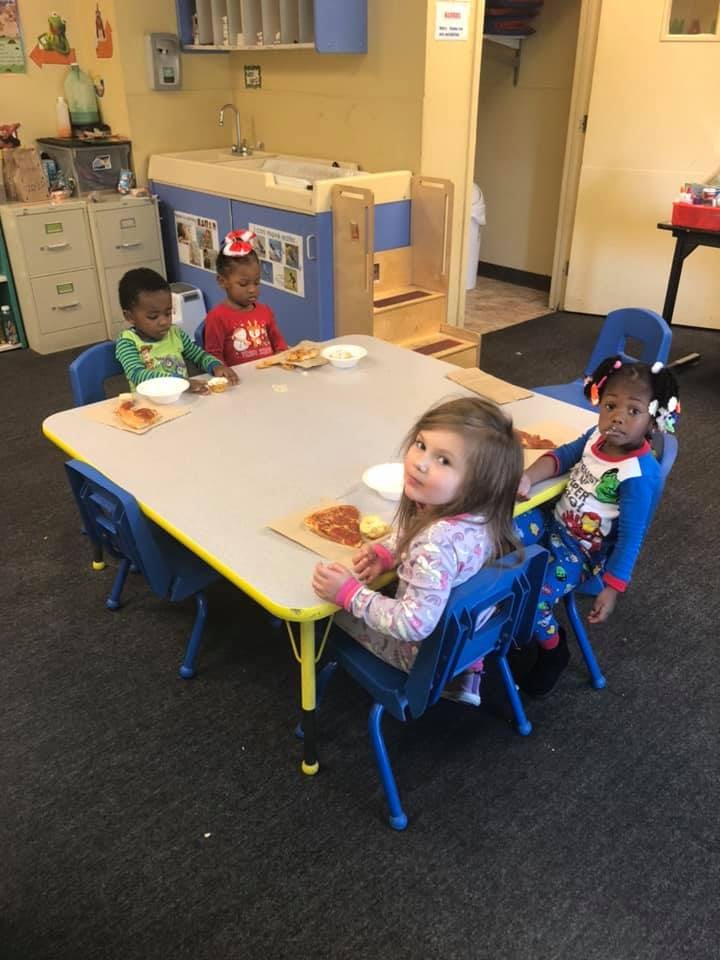 Four children sitting at a table in a classroom