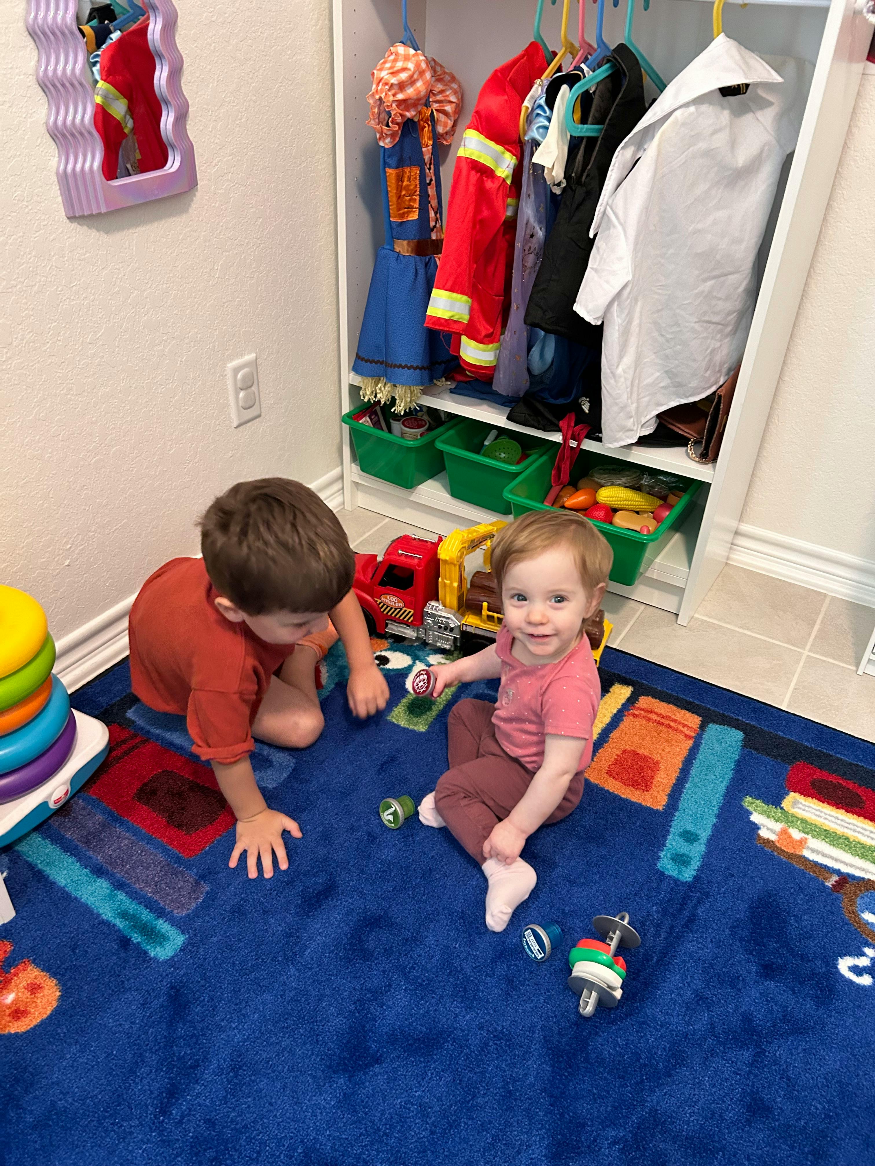 Two children playing with toys on a blue rug