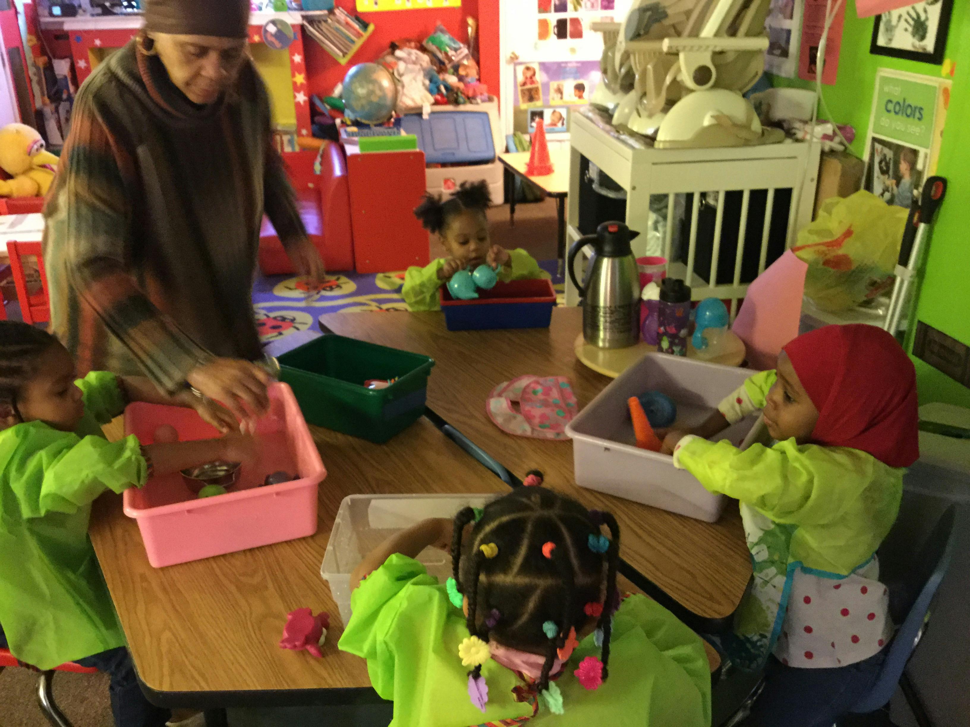 Adult and children at a table with colorful bins