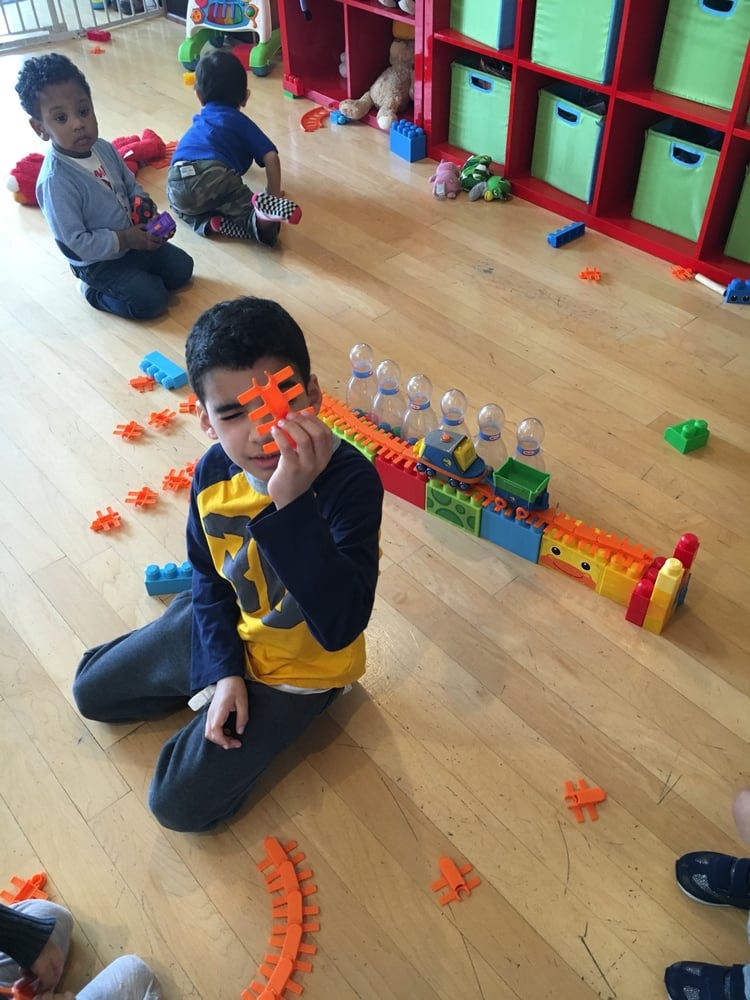 Child playing with building blocks on a wooden floor