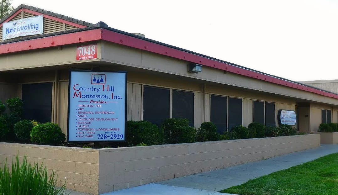 Building with a red roof and a sign that reads "Country Hill Montessori"