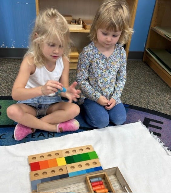 Two children playing with a colorful wooden block toy