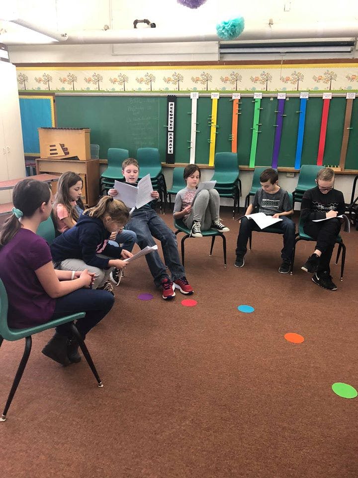 Group of children sitting in a classroom, reading and writing