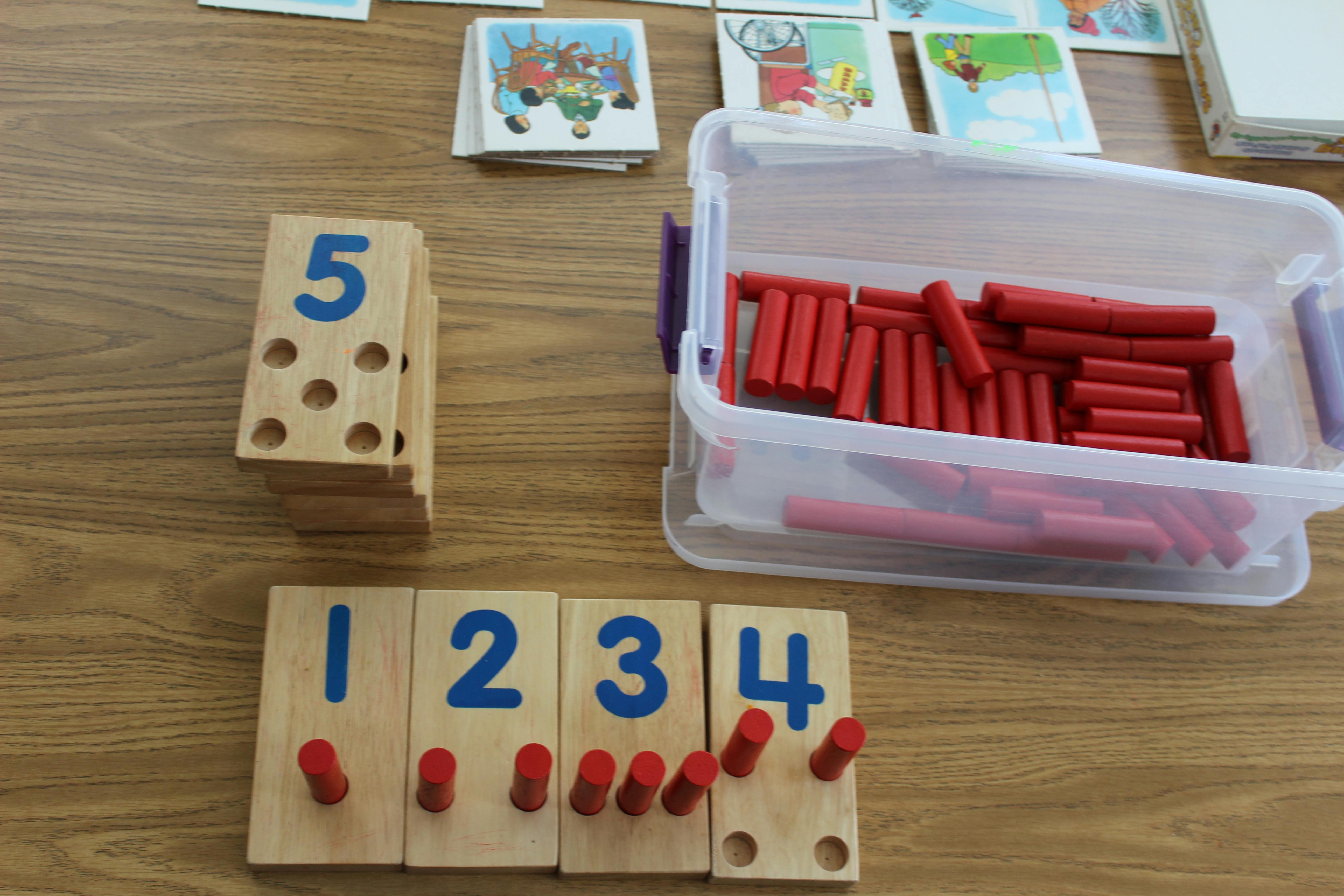 Wooden number blocks with pegs and a container of red counting sticks