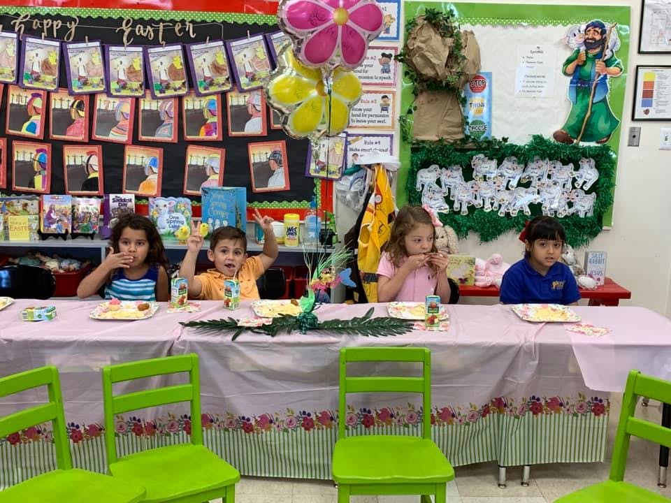 Four children sitting at a table in a classroom