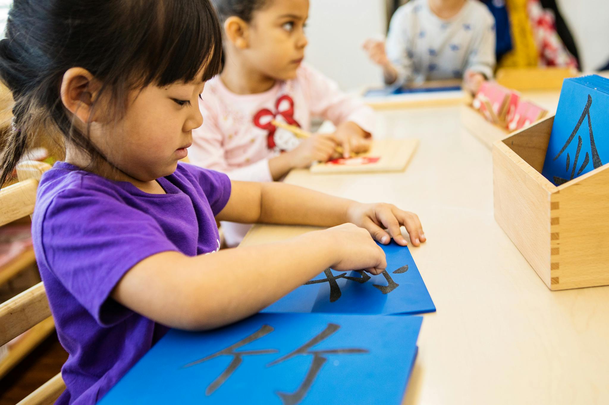 Child tracing characters on a blue board in a classroom