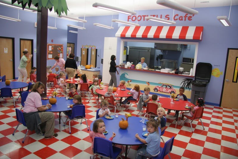 Children and adults in a brightly colored room with tables and a cafe counter