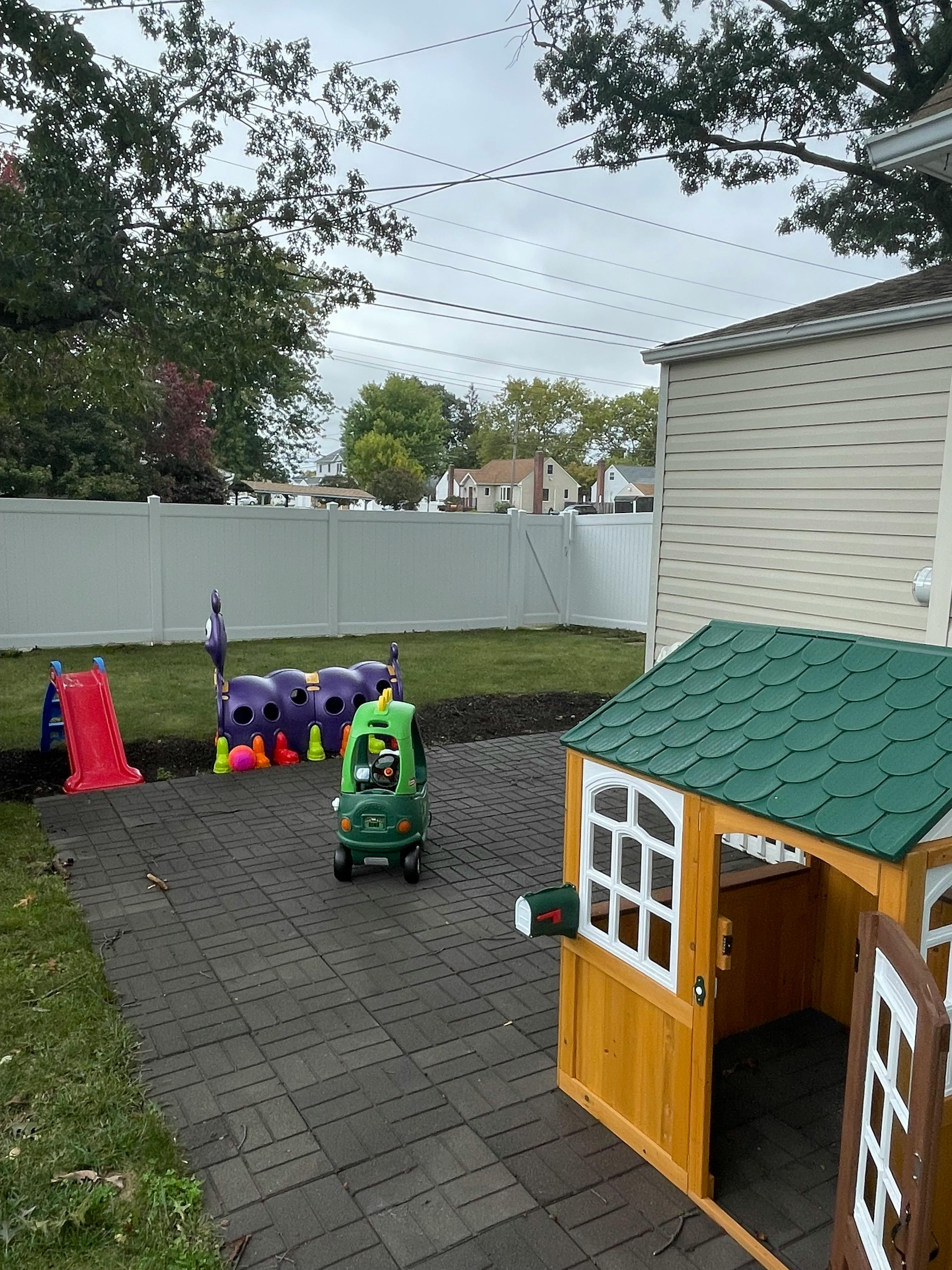 Backyard with a playhouse, toy car, and slide on a patio