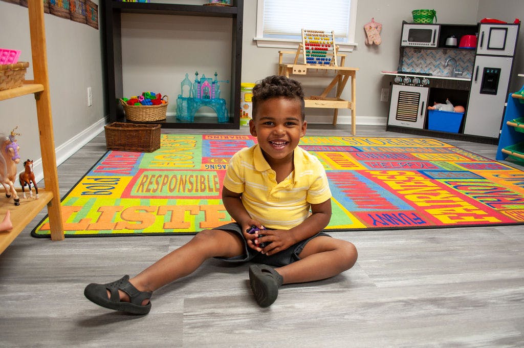 Child sitting on a colorful rug in a classroom
