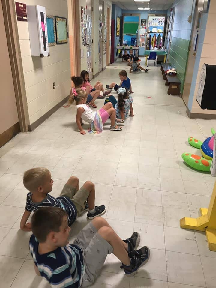 Children sitting and crawling on a hallway floor