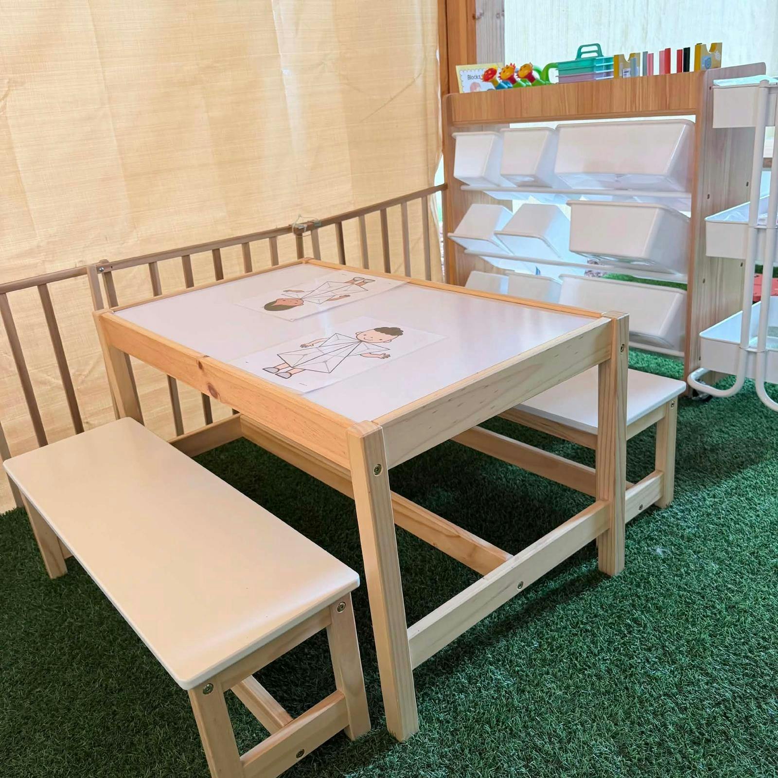 Wooden children's table and benches with drawing sheets on artificial grass