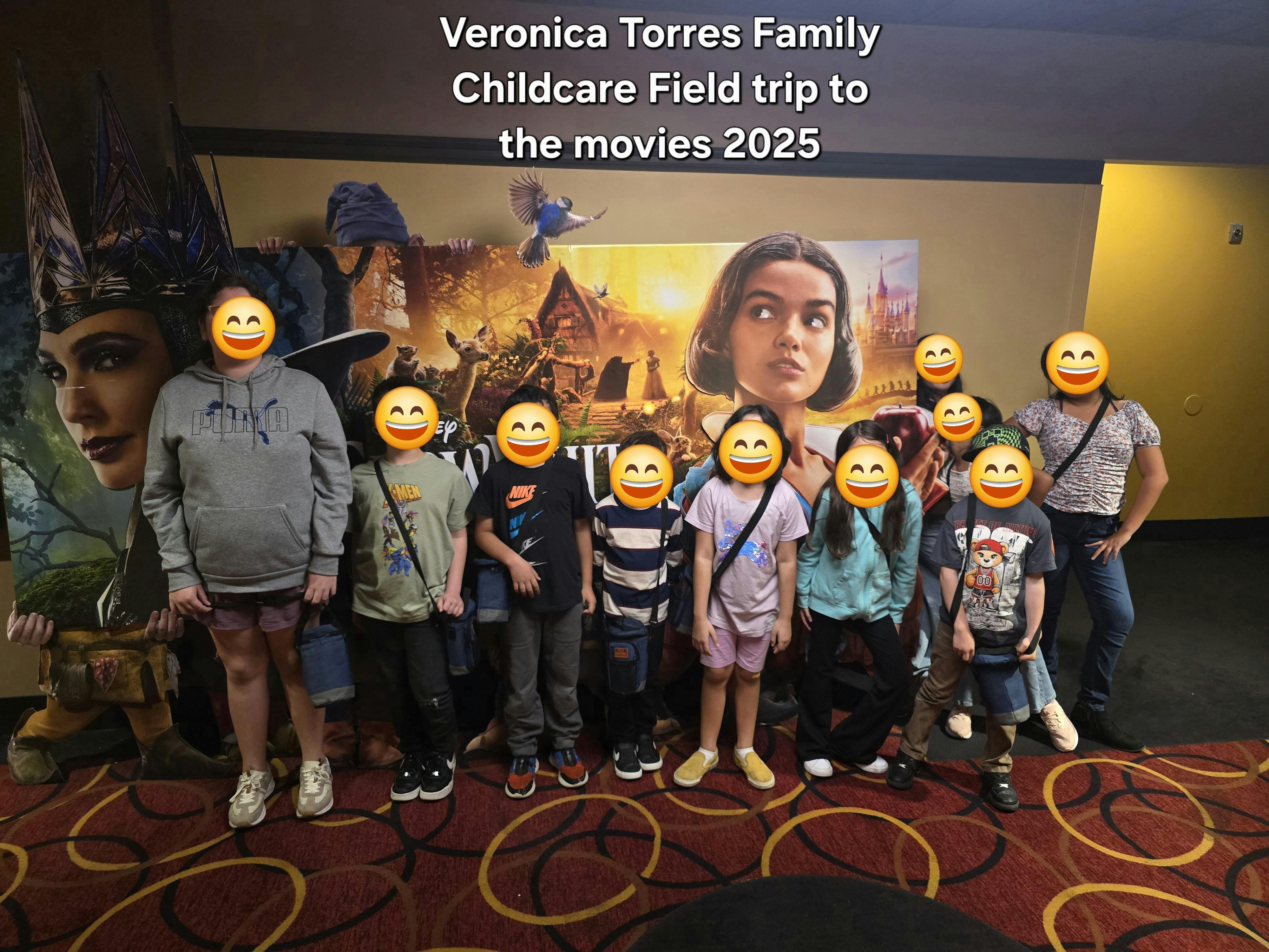 Group of children and adults standing in front of a movie poster