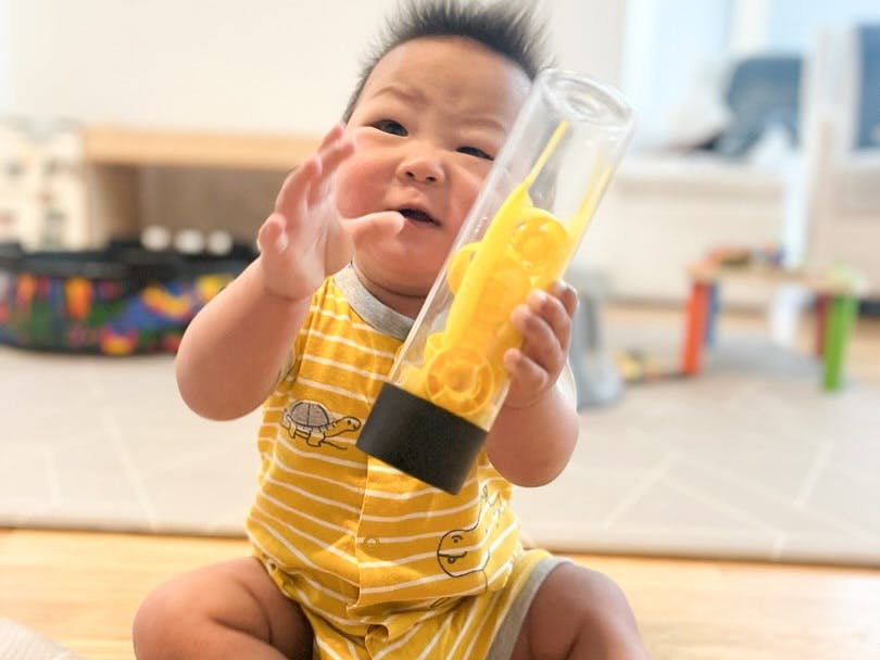 Child holding a clear bottle with yellow objects inside