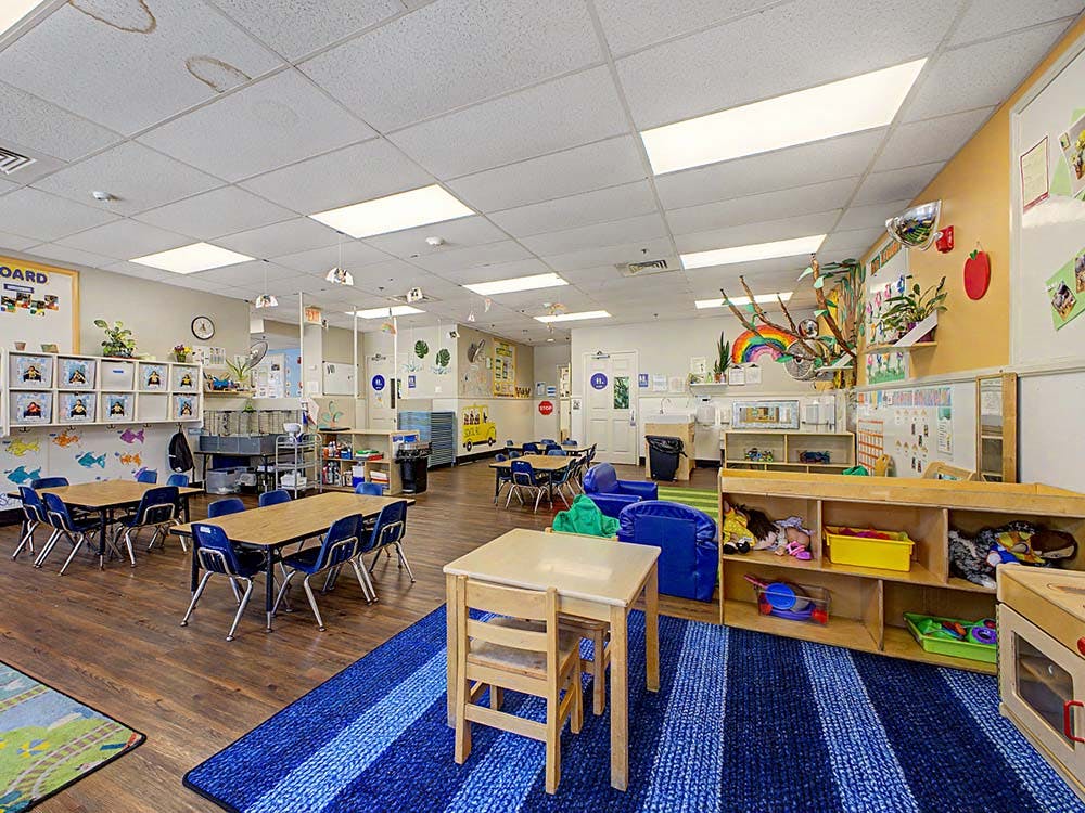 Colorful classroom with child-sized tables, chairs, and play areas