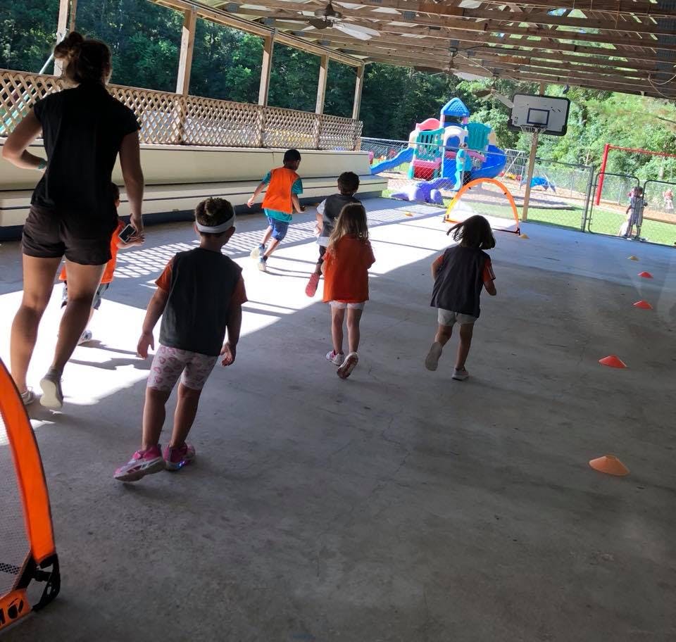 Adult and children running on a covered outdoor court