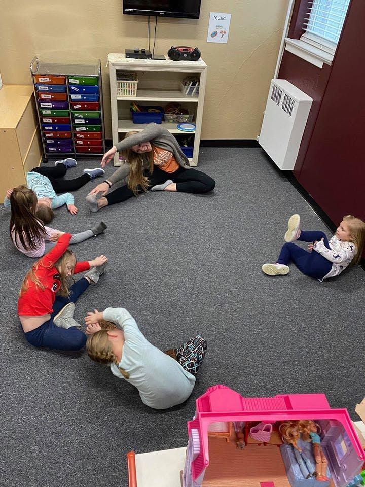 Adult and children stretching on a carpeted floor
