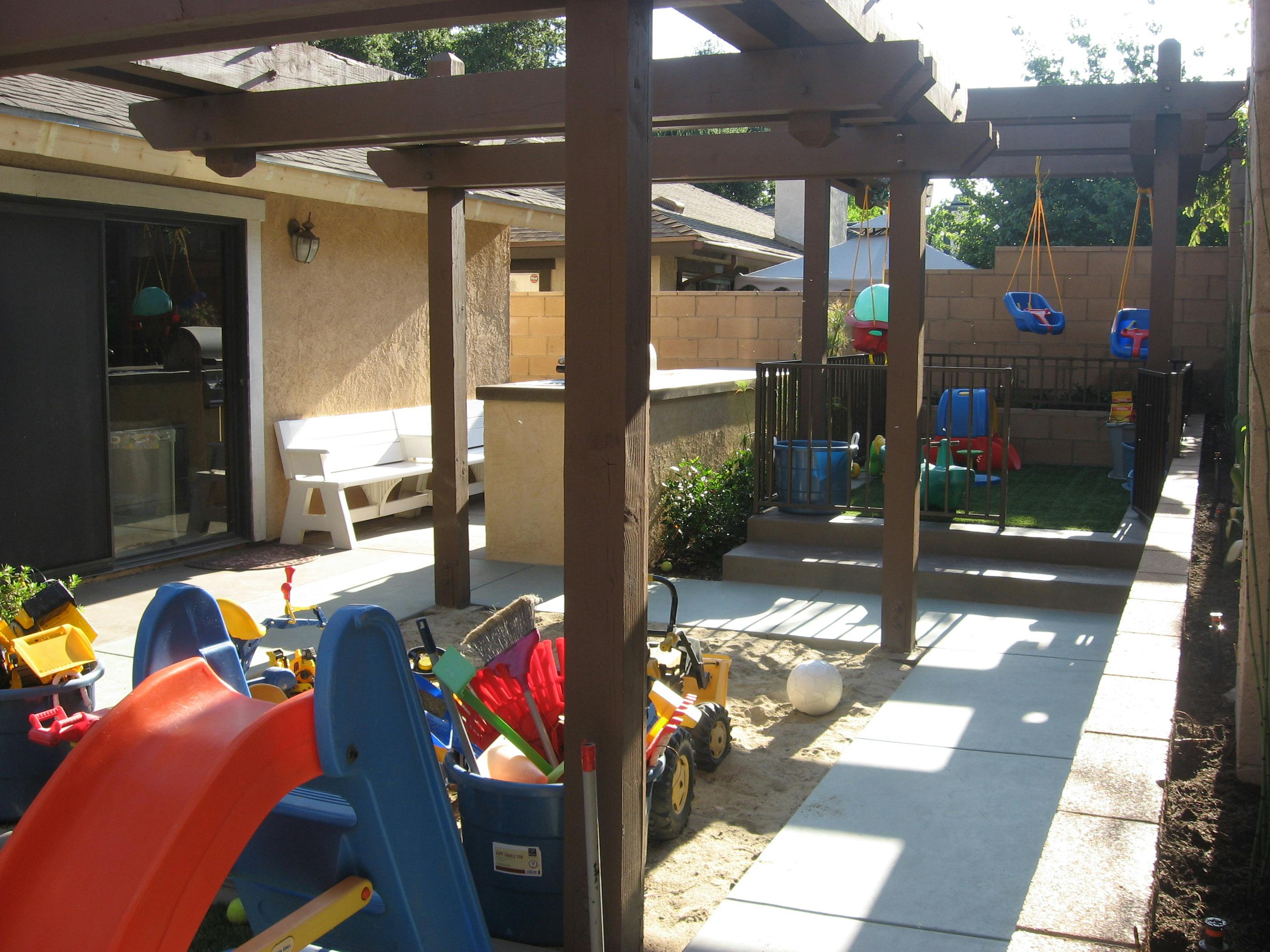Backyard patio featuring a wooden pergola and children's outdoor play equipment