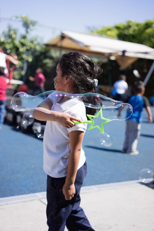 Child holding a star-shaped bubble wand with a large bubble