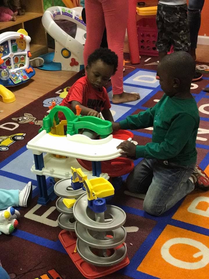 Two children playing with a toy car ramp in a classroom