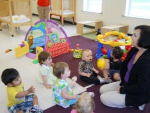 Adult and multiple children sitting on a rug in a room with toys