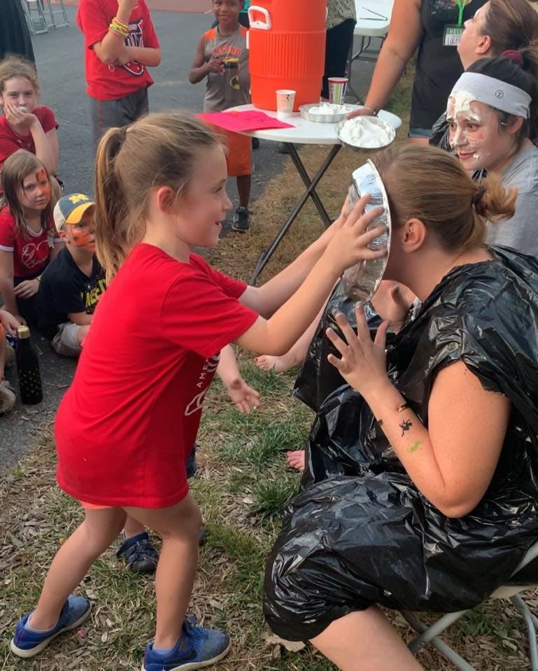 Child pushing a pie plate into a person's face