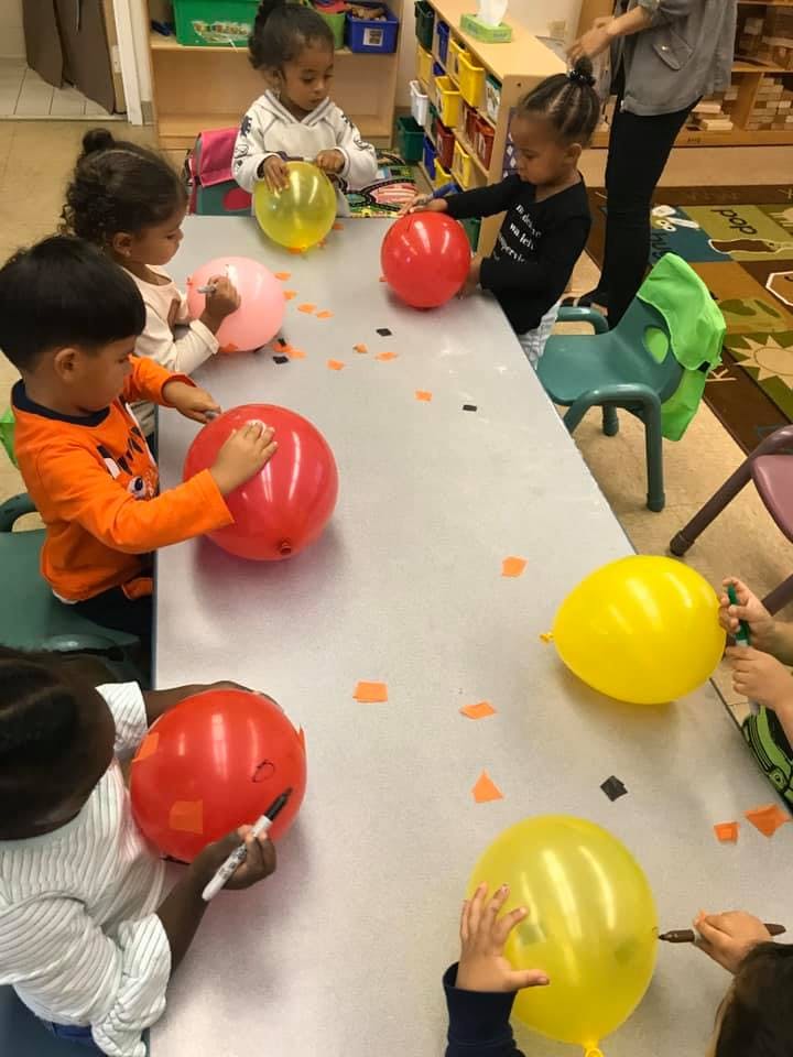 Children decorating balloons at a table