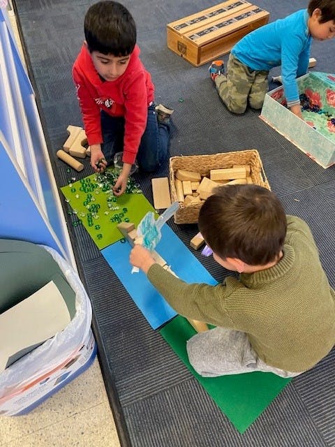 Children playing with small objects and wooden blocks on the floor