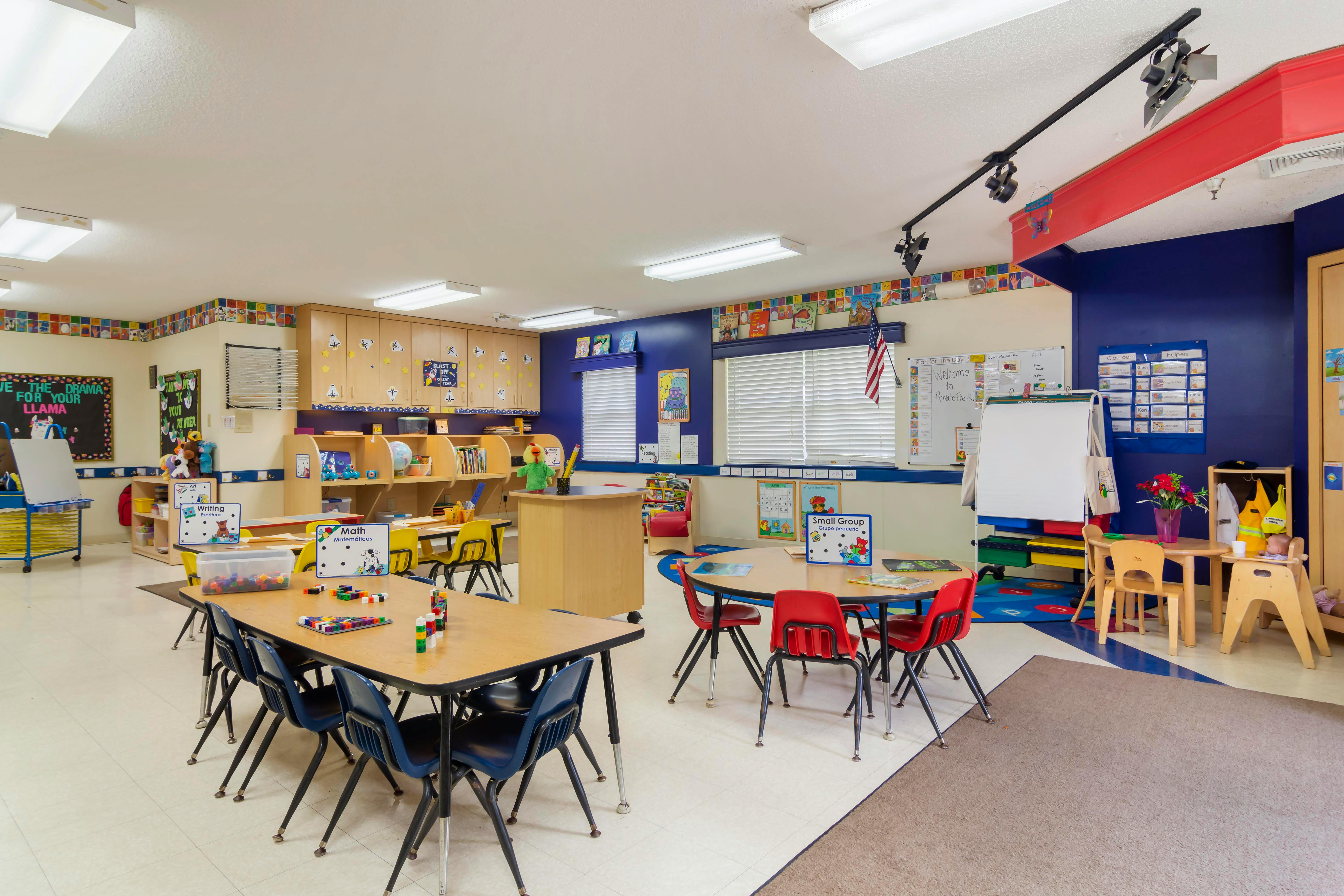 Classroom with multiple tables and chairs, various learning stations around the room