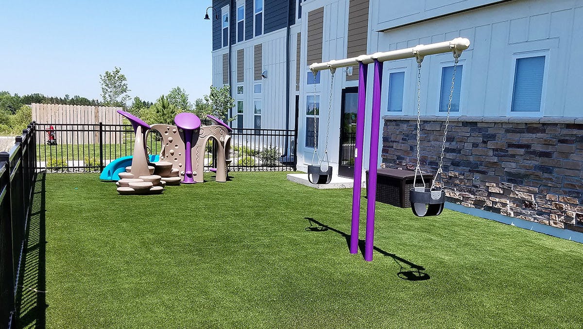 Playground with swings and climbing structure on artificial turf