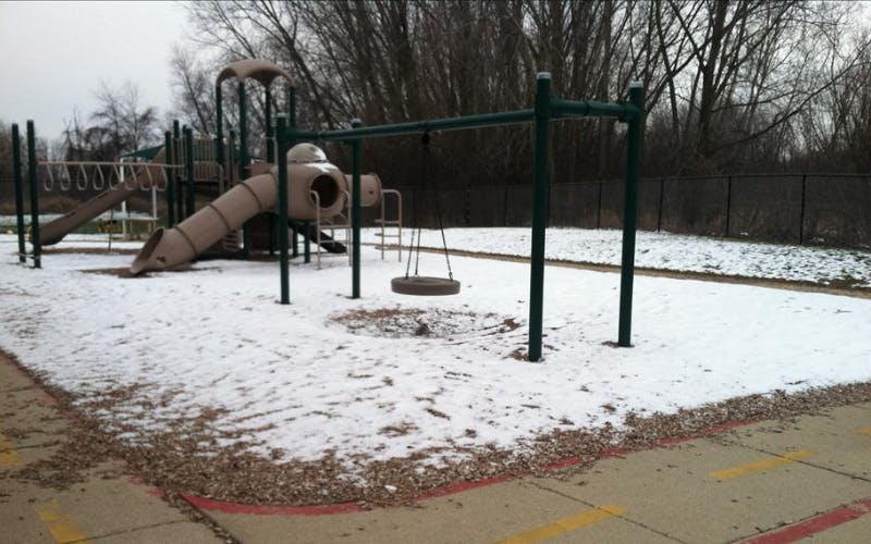 Snow-covered playground with slides, monkey bars, and a tire swing