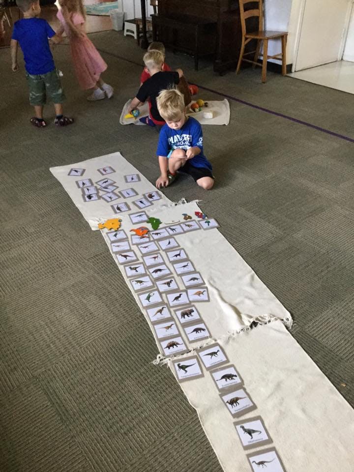 Child kneeling on floor playing with cards and toy animals