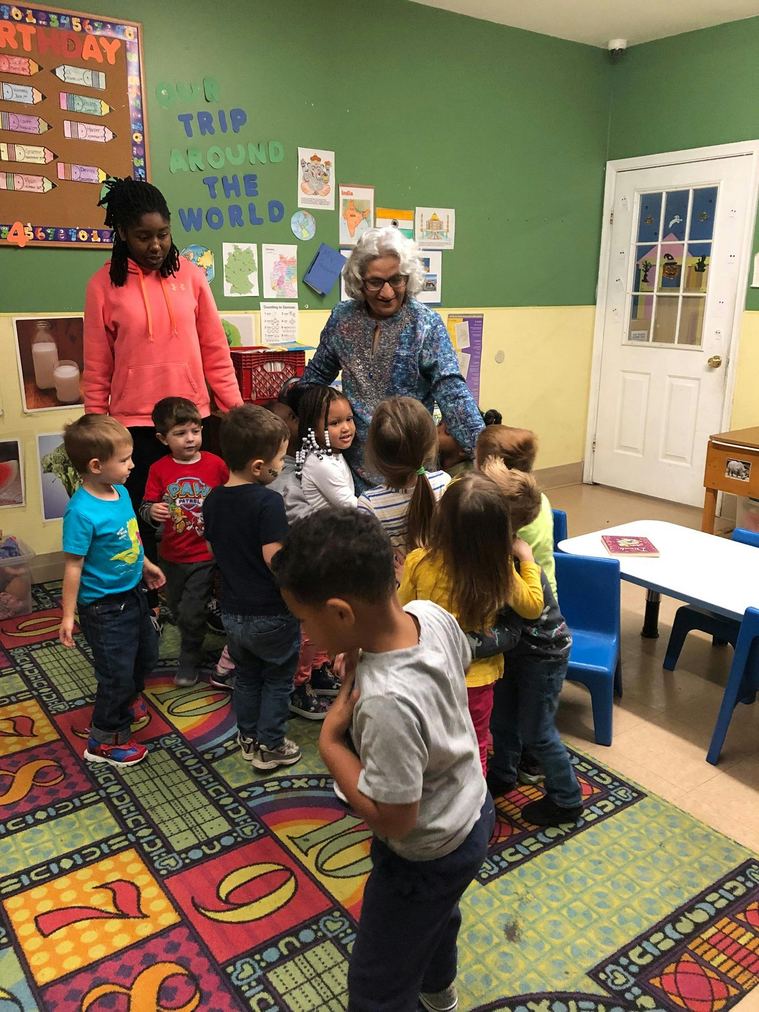 Two adults with a group of children in a classroom