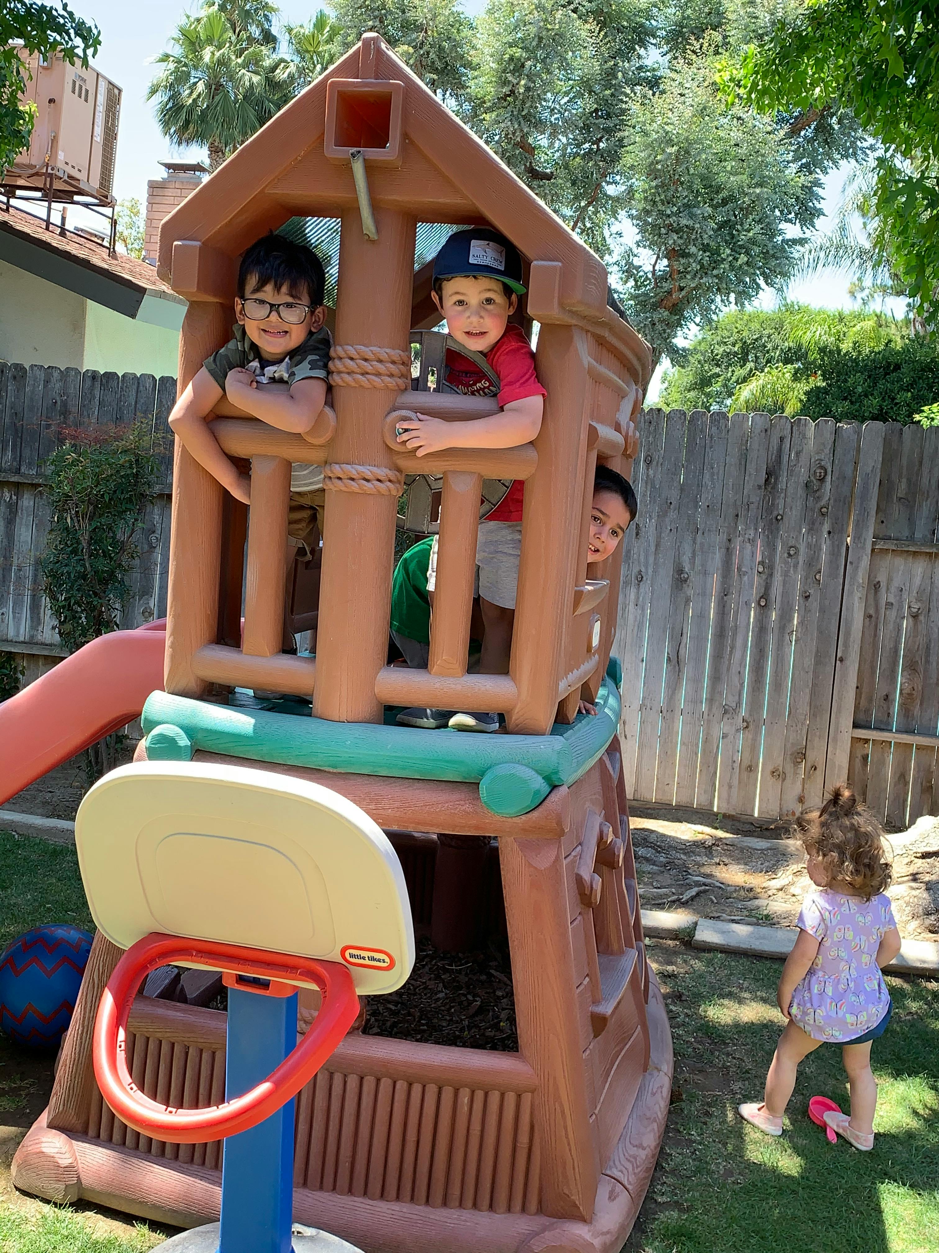 Children playing in a backyard playhouse