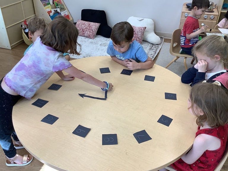 Children playing with a clock face on a round table