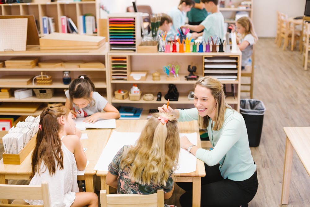 Adult and children working at tables in a classroom