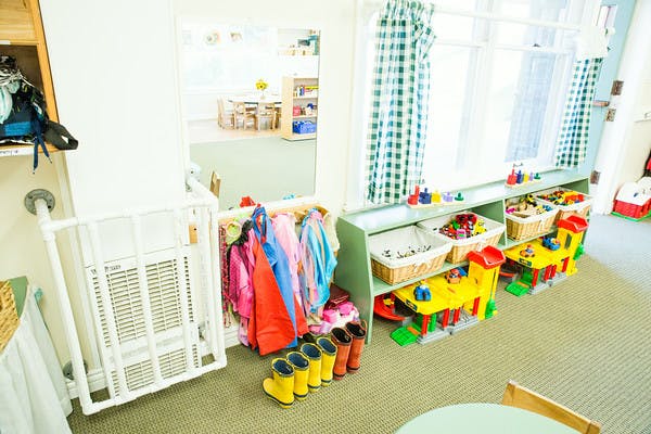 Children's clothing rack with boots and shelves with toys in a classroom