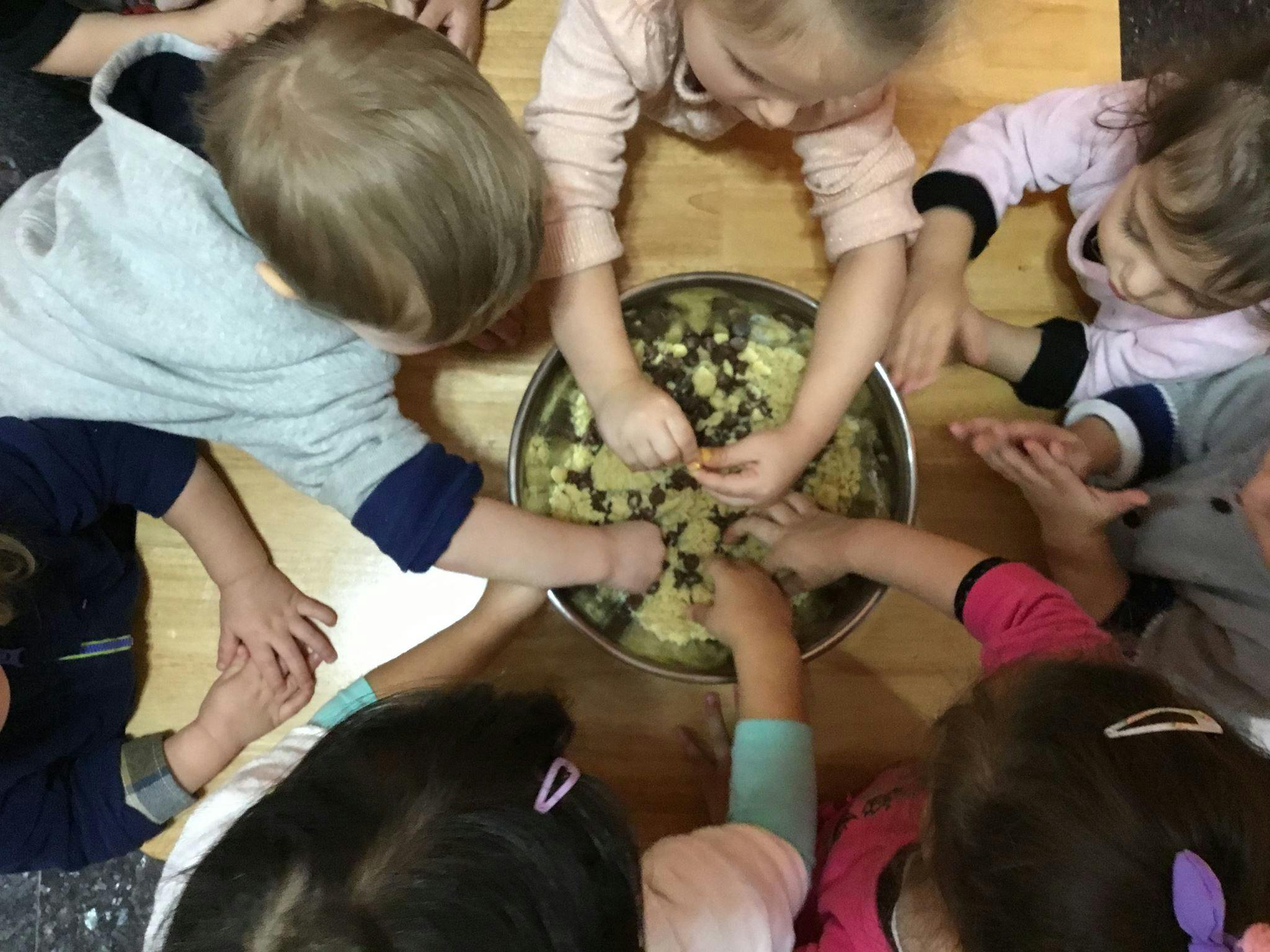 Children gathered around a bowl, mixing ingredients with their hands