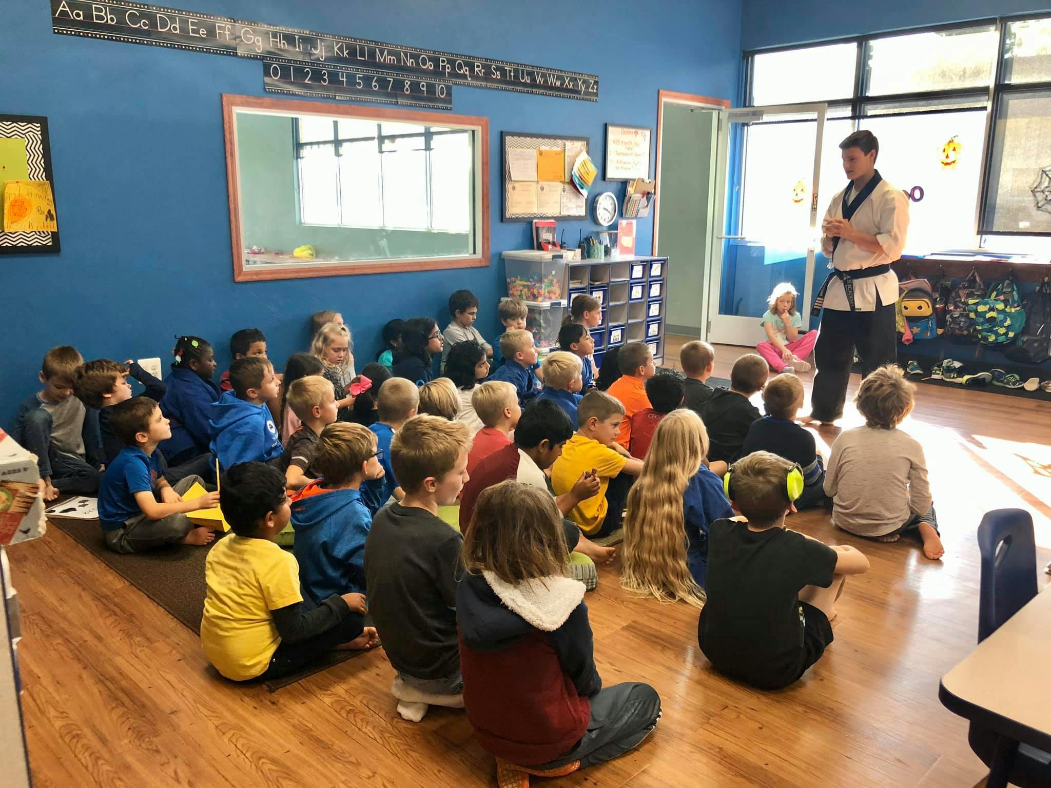 Adult in martial arts uniform teaching a group of children in a classroom