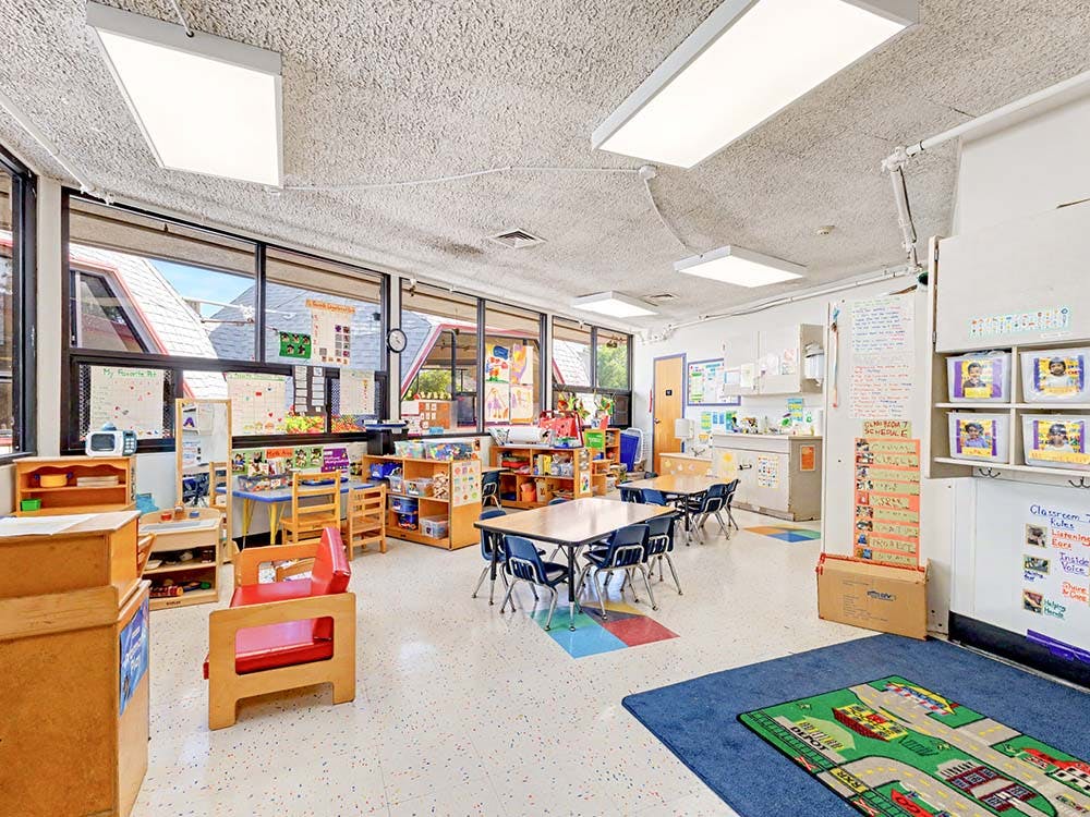 Empty classroom with small tables, chairs, and learning materials