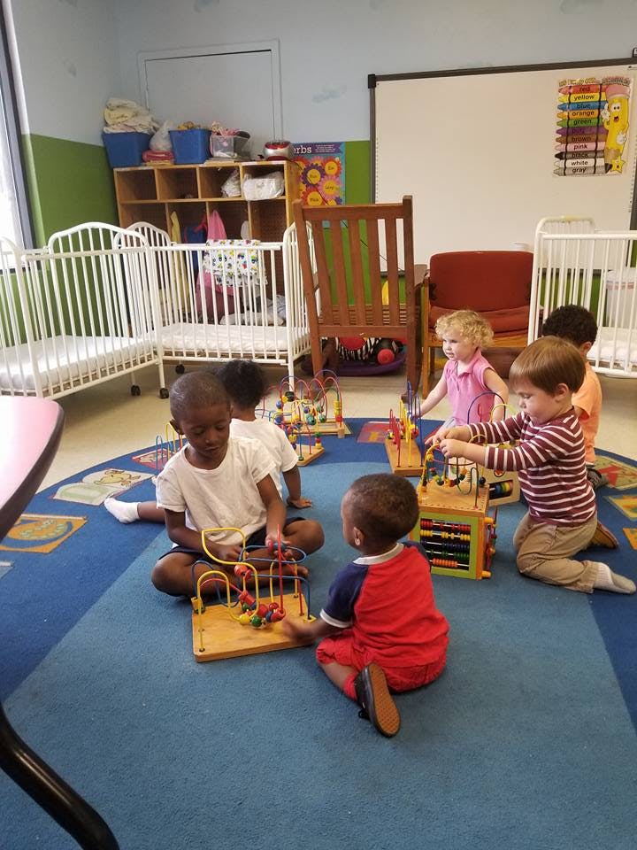 Children playing with toys on a rug in a classroom