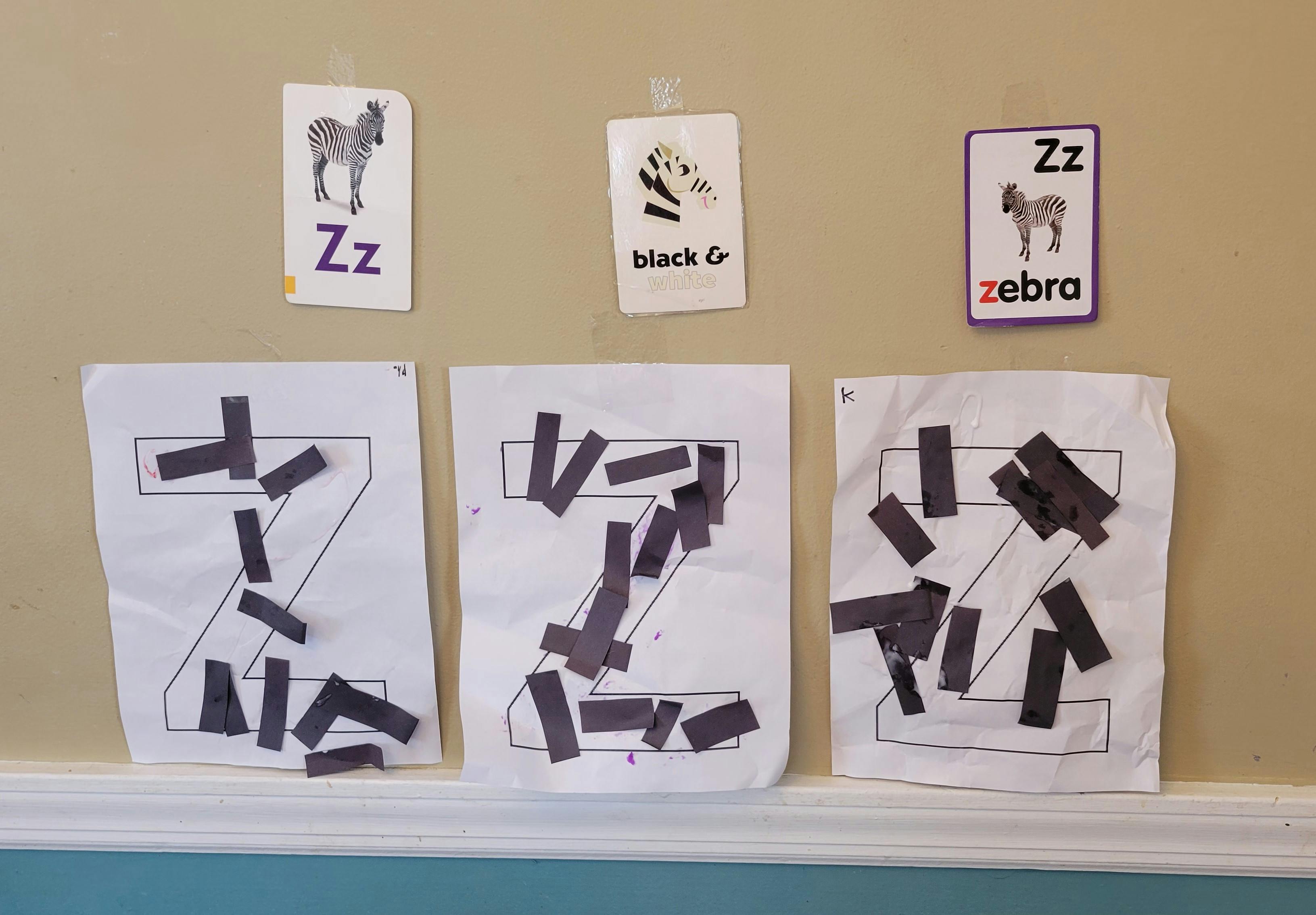Three letter Z crafts made from paper and black strips, with alphabet cards above