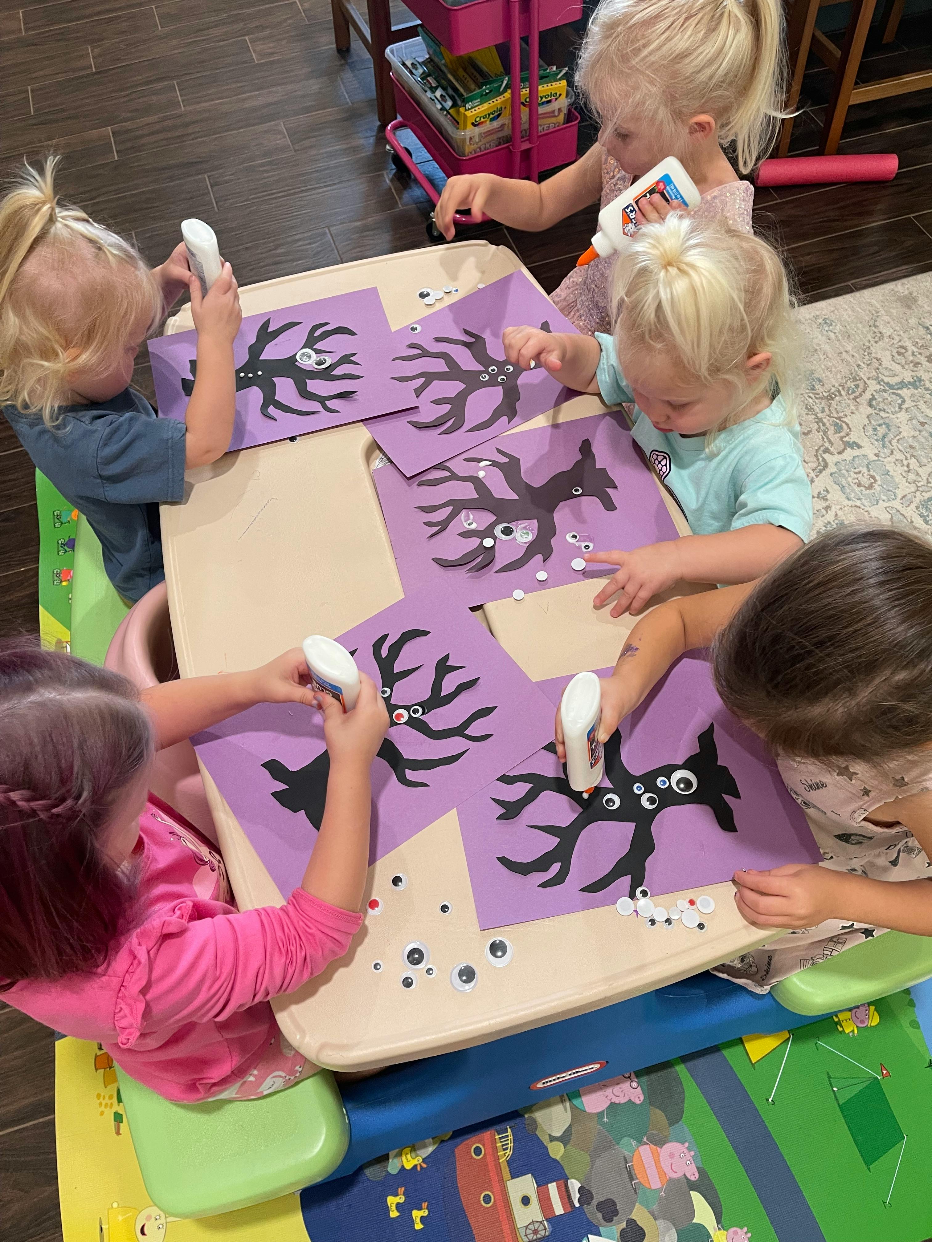Children gluing googly eyes onto paper tree cutouts