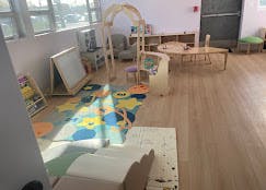 Empty classroom with a colorful rug, small tables, and chairs
