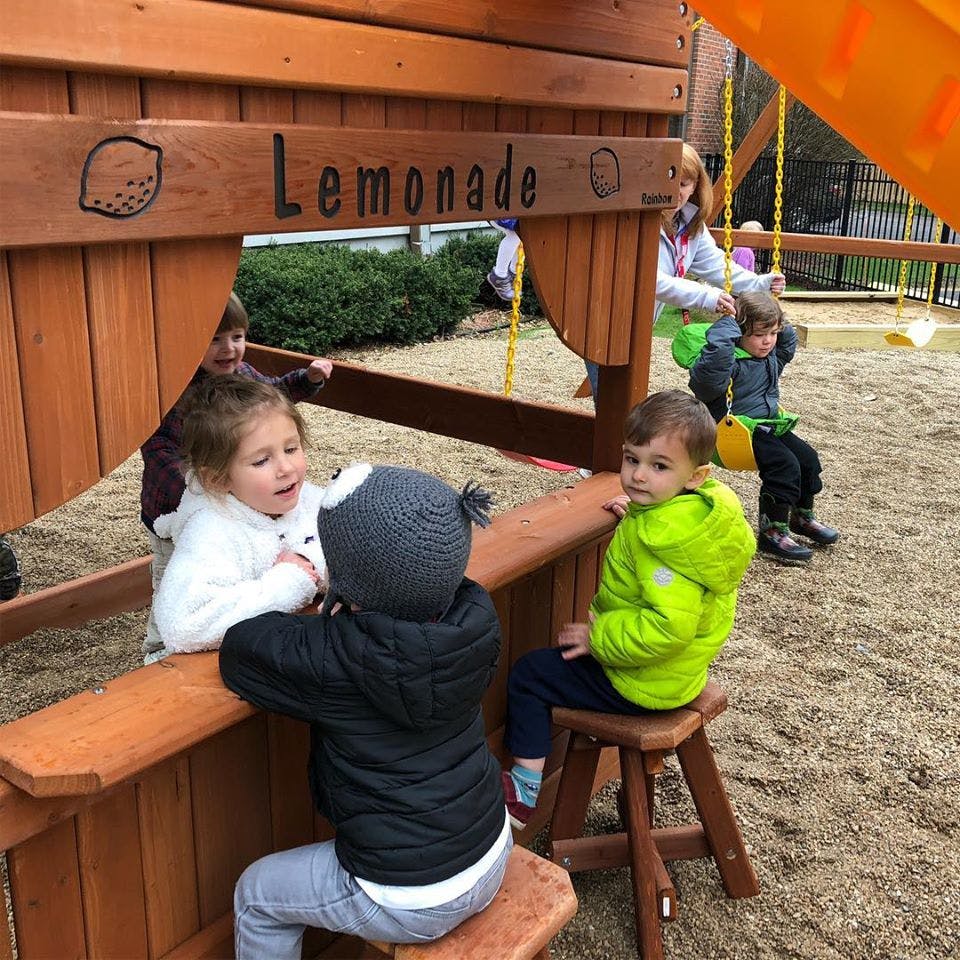 Children playing at a wooden lemonade stand